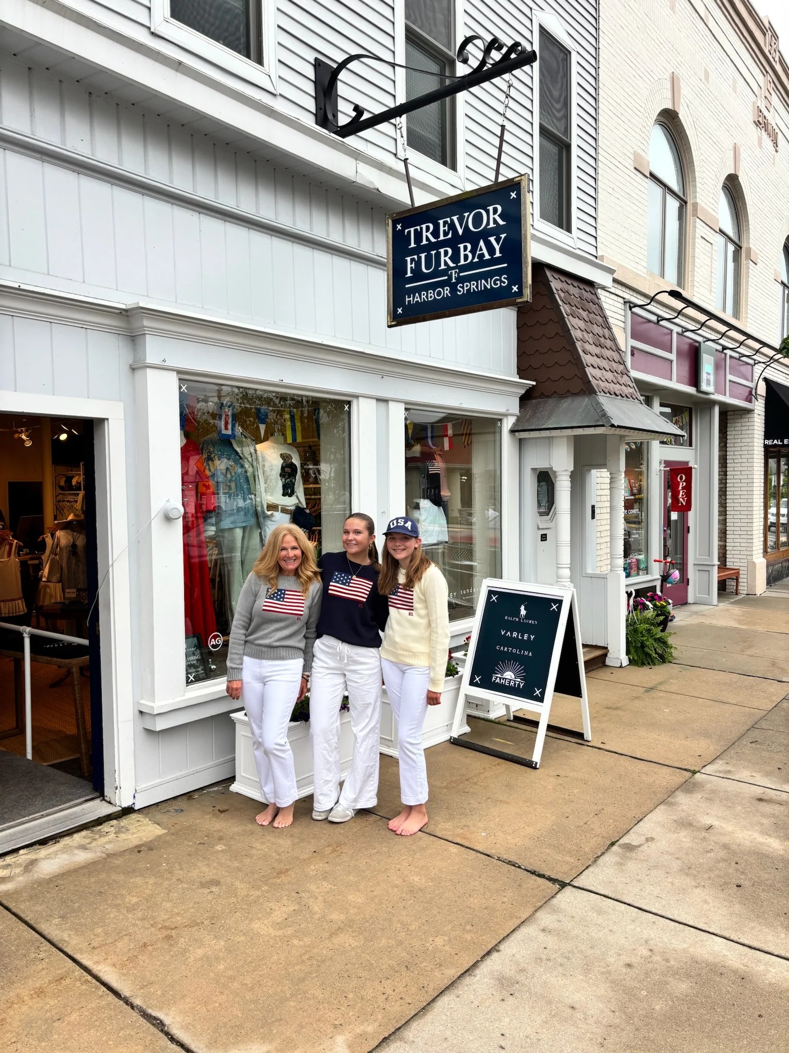 Three women in american flag sweaters model style outside Trevor Furbay in Harbor Springs.